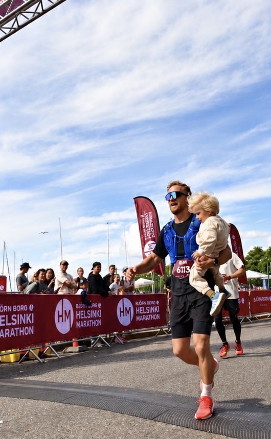 Behar crossing the Helsinki Marathon finish carrying his child